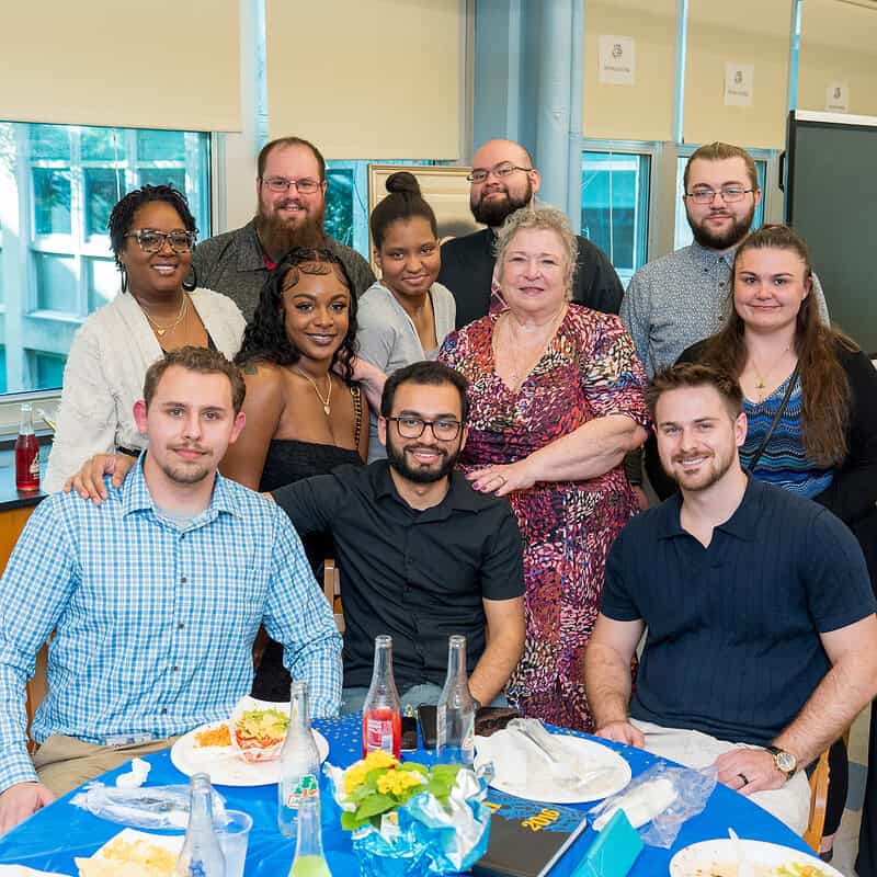 Photo of Philadelphia Academies alumni gathered around a table of food and drinks.
