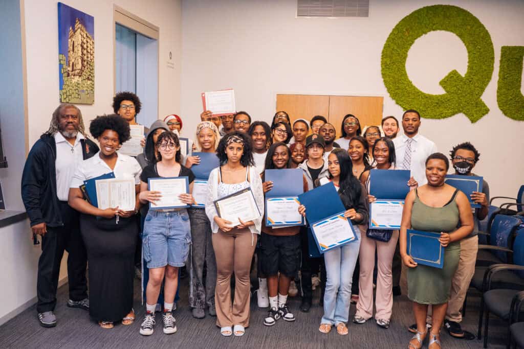A group of students and teachers stand together showing their certificates.