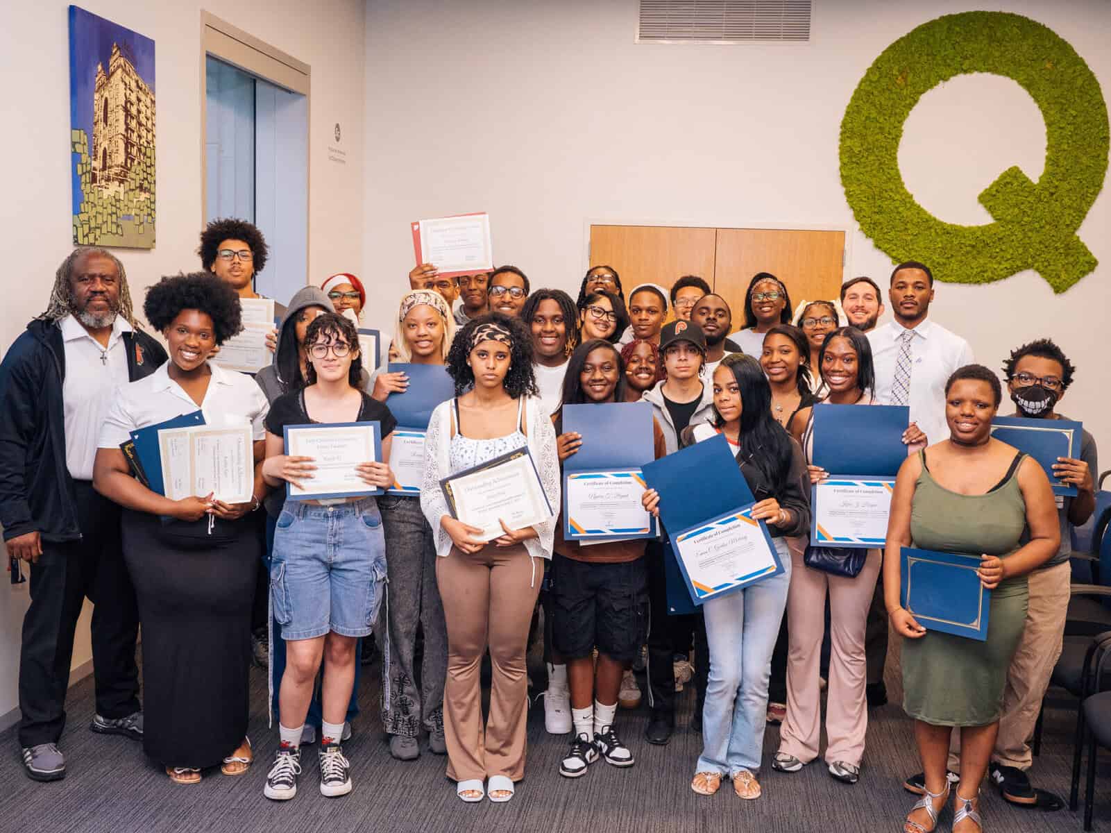 Rows of students hold up their graduation certificates.