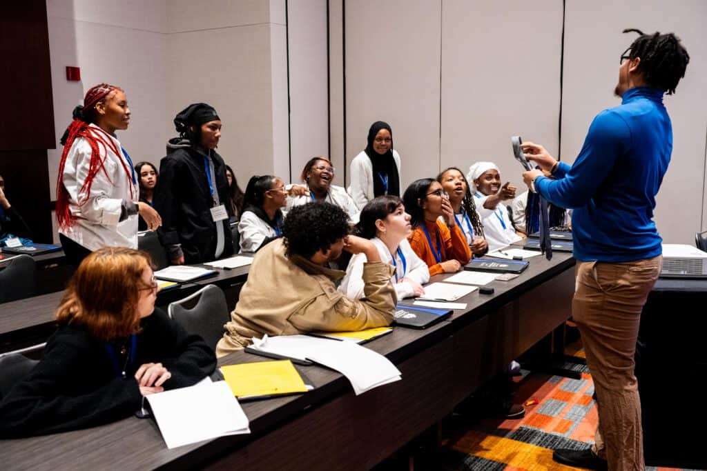 A teacher lectures students in a classroom.
