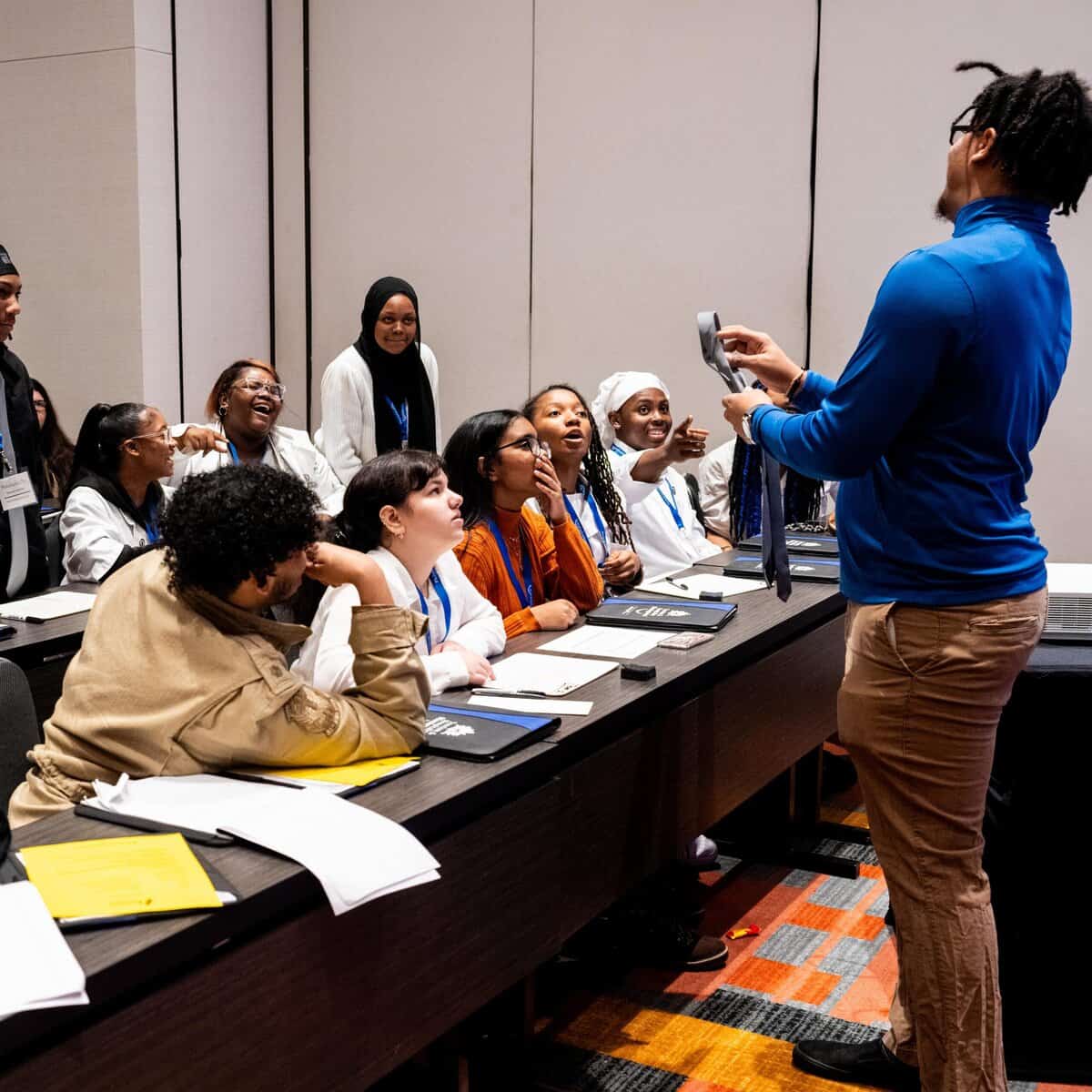 Teacher who is part of a school partnership program is showing something to students in a classroom lecture.