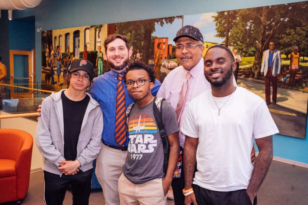 A group of students and two teachers all pose for a photo in a classroom.

